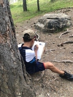 Enfant qui écrit en plein air durant l'atelier d'Elsa Valentin