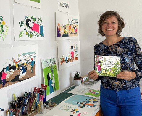 Emmanuelle Houssais posant dans son atelier avec ses illustrations